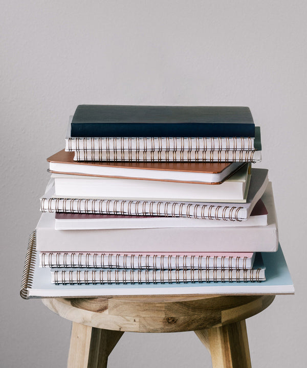 A stack of notebooks sits on a chair